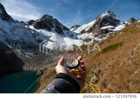 Mountain range and tourist hand with compass on foreground. Nature reserve, travel concept. Landscape photography 123397936