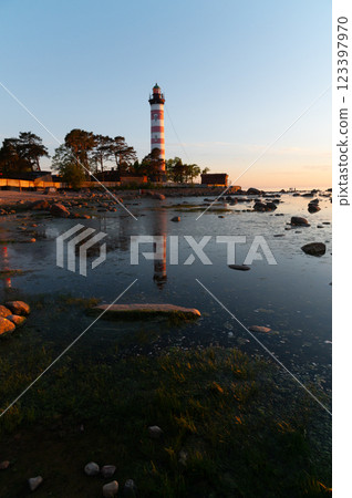 Dramatic sunset at a lighthouse on the coast. Lighthouse with white and red stripes among trees 123397970