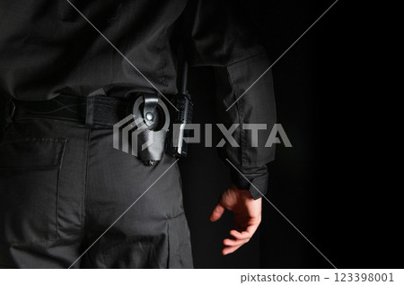 security guard controlling the premises. bodyguard in black uniform on black background, with handcuffs on his belt security guard controlling the premises. bodyguard in black uniform on black background, with handcuffs on his belt 123398001