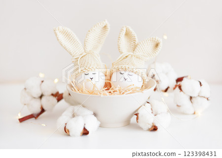 Easter eggs in crochet knitted hats with rabbit ears in nest. Easter celebration concept Easter eggs in crochet knitted hats with rabbit ears in nest. Easter celebration concept 123398431
