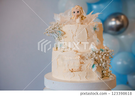 Elegant Two-Tiered Cake with Child Figurine and Floral Accents 123398618