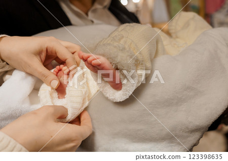 Tender Moments: A Caregiver Dressing an Infant in Cozy Knitwear Tender Moments: A Caregiver Dressing an Infant in Cozy Knitwear 123398635