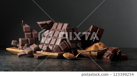 Broken dark chocolate bar and cocoa powder on a black background. 123399254