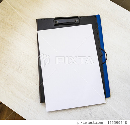 Shot of the plastic folder on the office desk with paper clip holder on the top and other office items. A4 size paper mock up. 123399548