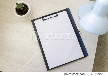 Shot of the plastic folder on the office desk with paper clip holder on the top and other office items. A4 size paper mock up. 123399552