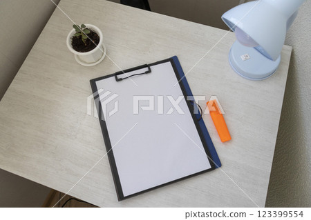 Shot of the plastic folder on the office desk with paper clip holder on the top and other office items. A4 size paper mock up. Shot of the plastic folder on the office desk with paper clip holder on the top and other office items. A4 size paper mock up. 123399554