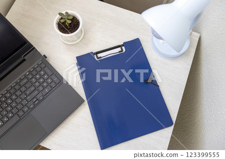 Shot of the plastic folder on the office desk with paper clip holder on the top and other office items. A4 size paper mock up. 123399555