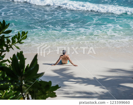 Handsome man sitting on stunning white sand beach 123399660