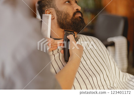 A Skilled Barber Elegantly Trimming a Stylish Beard at a Modern Salon Venue Today 123401172