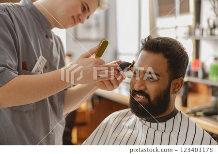 A Skilled Barber Providing Exceptional Haircut and Grooming Services at a Modern Salon 123401178