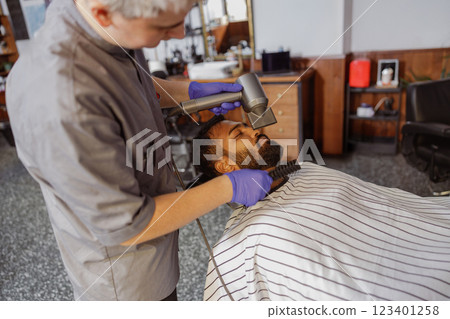 A skilled barber is giving a precise haircut in a cozy and inviting salon atmosphere A skilled barber is giving a precise haircut in a cozy and inviting salon atmosphere 123401258