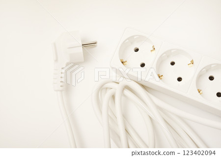 An extension cord with three sockets. White wire with sockets on a white background. An extension cord with three sockets. White wire with sockets on a white background. 123402094