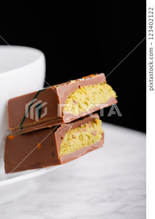 Dubai chocolate with pistachio filling on a white plate on a black background 123402122