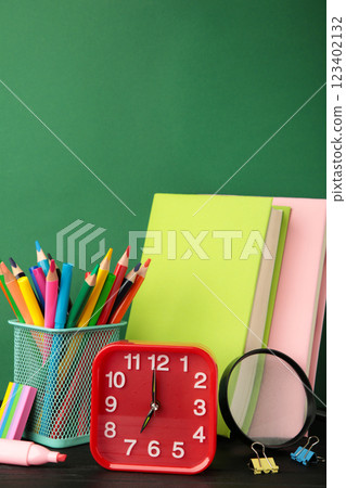 Red alarm clock and school accessories on a green background. Back to school concept. Red alarm clock and school accessories on a green background. Back to school concept. 123402132