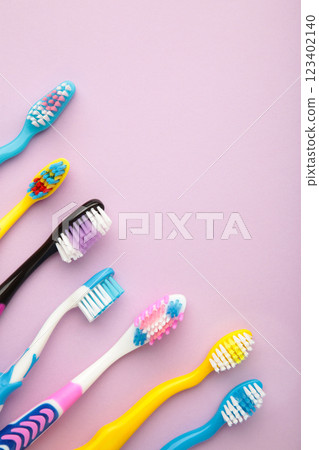 Colorful toothbrushes on purple background. Vertical photo 123402140