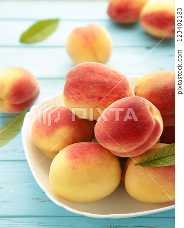 Plate of ripe peaches on blue background. Vertical photo 123402183