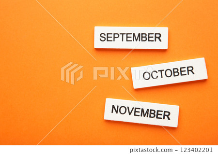 Wooden cubic of september, october, november on orange background. Autumn month. 123402201