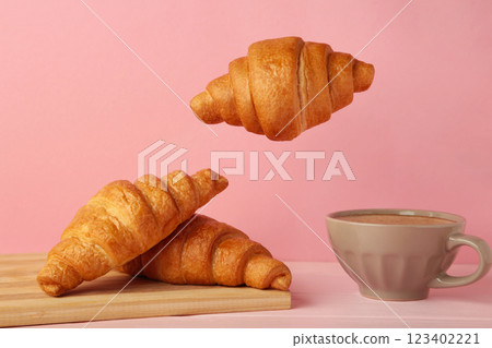 Flying croissant with coffee on pink background. 123402221