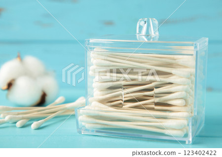 Cotton sticks in containers with cotton flower on blue background. Cotton sticks in containers with cotton flower on blue background. 123402422