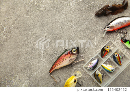 Nikolaev, Ukraine - 08 july, 2022: Colorful fishing lures, wobbler, spinner, on grey wood desk different fishing baits 123402432