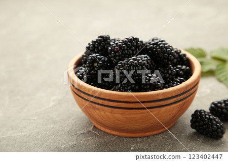 Ripe blackberries with leaves in a wooden bowl on grey wooden background. Ripe blackberries with leaves in a wooden bowl on grey wooden background. 123402447