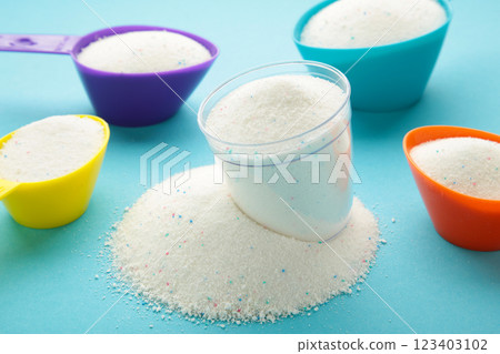 Measuring scoop with laundry powder on blue background. 123403102