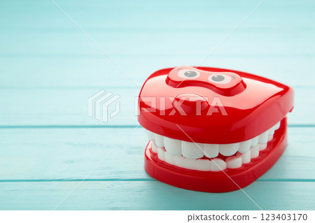 Plastic toy teeth on blue background. Abstract minimal composition. 123403170