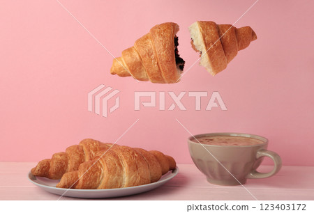 Flying croissant with coffee on pink background. 123403172