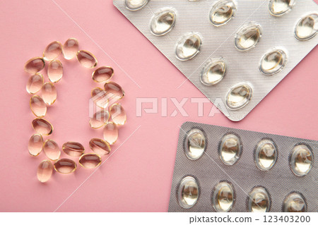 Vitamin D capsules in the shape of letter D on pink background 123403200