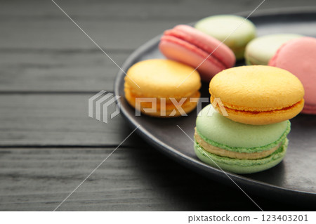 Colorful macarons cakes on black background. Small French cakes on plate. Space for text 123403201
