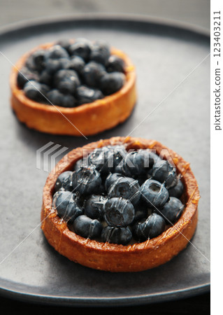 Blueberry tartlets on dark plate. Homemade tarts with black berries. 123403211