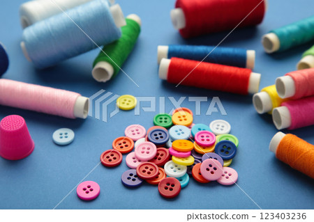 Colorful buttons with colorful thread on dark blue background Colorful buttons with colorful thread on dark blue background 123403236