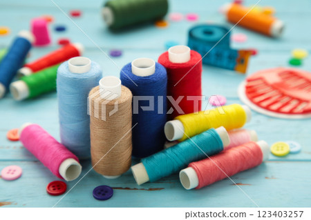 Sewing supplies on blue background: sewing thread, scissors, a large spool of thread, pieces of cloth, needles,centimeter, buttons 123403257