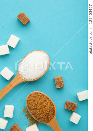 White and brown sugar in wood spoon on blue background. 123403497