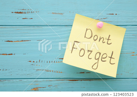 Reminder with text 'Don't forget' on a pink memo on blue background Reminder with text 'Don't forget' on a pink memo on blue background 123403523