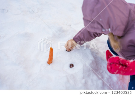 Girl building a snowman in Spindleruv Mlyn, Czech Republic. Girl building a snowman in Spindleruv Mlyn, Czech Republic. 123403585