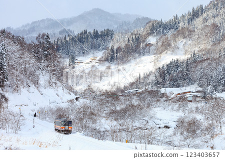 A diesel train on the Oito Line crosses the snow-covered mountains and comes down into the city. 123403657
