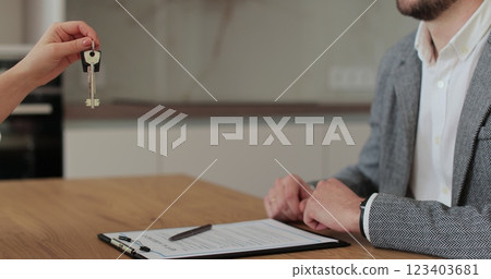 Close up of woman realtor gives keys to the man who buys a new house. Real estate, property purchase, mortgage concept. Close up of woman realtor gives keys to the man who buys a new house. Real estate, property purchase, mortgage concept. 123403681