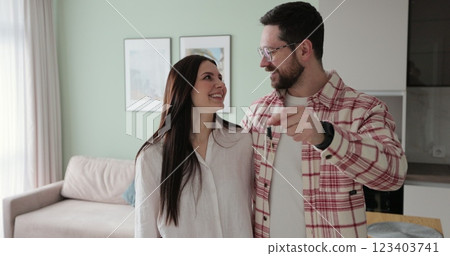 Happy couple owners of a new apartment show the key looking at the camera. Buying first family real estate, move in new home. Home buying concept. 123403741