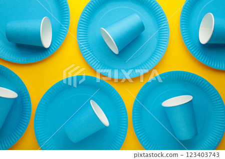 Eco-friendly disposable utensils made of craft paper on yellow background. Blue plates and paper cups 123403743