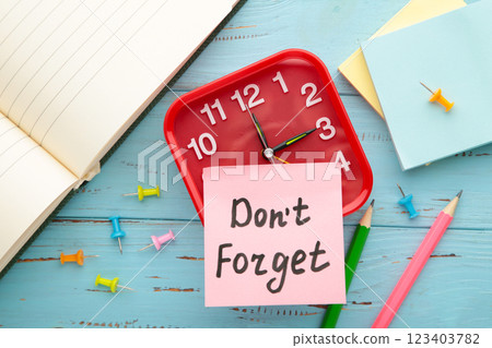 Alarm clock and reminder note with phrase Don't forget on light blue background Alarm clock and reminder note with phrase Don't forget on light blue background 123403782
