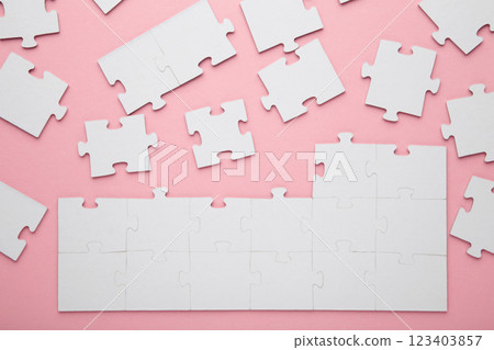 Unfinished white jigsaw puzzle pieces on pink background Unfinished white jigsaw puzzle pieces on pink background 123403857