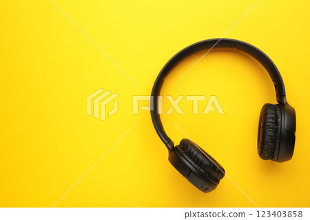 Black, modern wireless headphones on a yellow background. 123403858