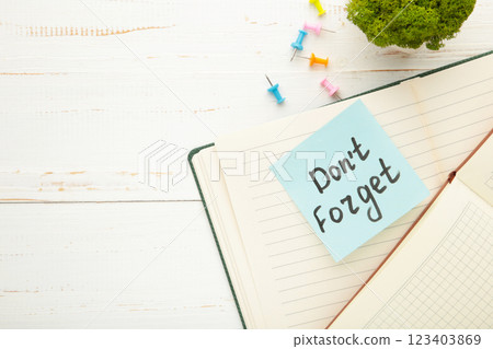 Open notepad and sticky notes with word don't forget on white background Open notepad and sticky notes with word don't forget on white background 123403869