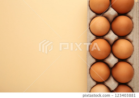 Chicken eggs in an open egg carton on beige. Top view with copy space. Natural healthy food and organic farming concept. 123403881
