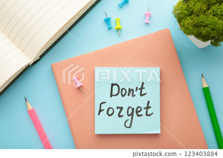 Open notepad and sticky notes with word don't forget on blue background Open notepad and sticky notes with word don't forget on blue background 123403884