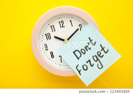 Alarm clock and reminder note with phrase Don't forget on yellow background Alarm clock and reminder note with phrase Don't forget on yellow background 123403885
