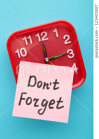 Alarm clock and reminder note with phrase Don't forget on light blue background Alarm clock and reminder note with phrase Don't forget on light blue background 123403887