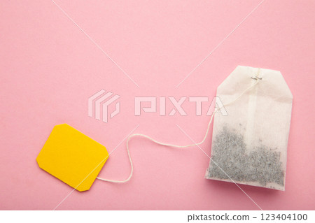 Tea bag with yellow blank label on pink background. Copy space for text. Tea bag with yellow blank label on pink background. Copy space for text. 123404100