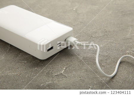 Portable powerbank with usb cable on grey background. 123404111